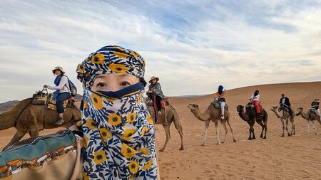 サハラ砂漠でラクダに乗る筆者、世界一周旅行中の浦上早苗氏