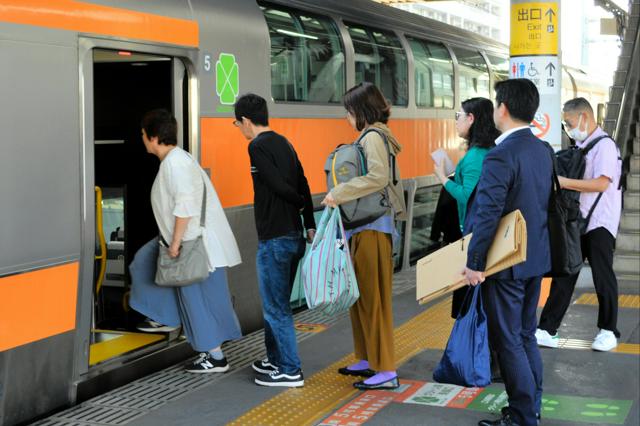 早朝、JR河辺駅でグリーン車に乗り込む通勤客。青梅市の通勤支援金申請急増との関連が指摘される。
