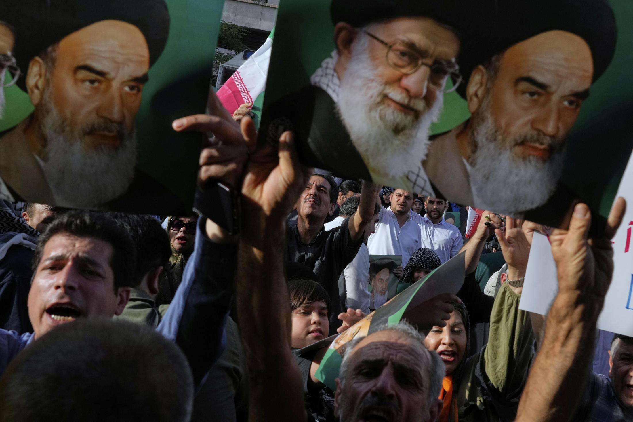 米国による核施設攻撃に抗議し、イラン最高指導者や革命指導者のポスターを掲げるテヘランのデモ隊