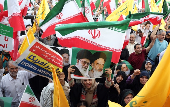 イランの首都テヘランで開かれた集会。参加者が最高指導者ハメネイ師らの肖像画を掲げる様子。