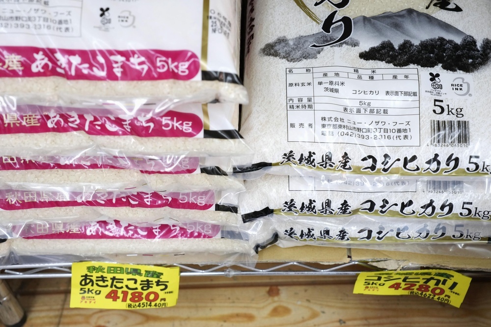 スーパーの店頭に並べられた様々な銘柄のコメ袋、高止まりする小売価格を示唆