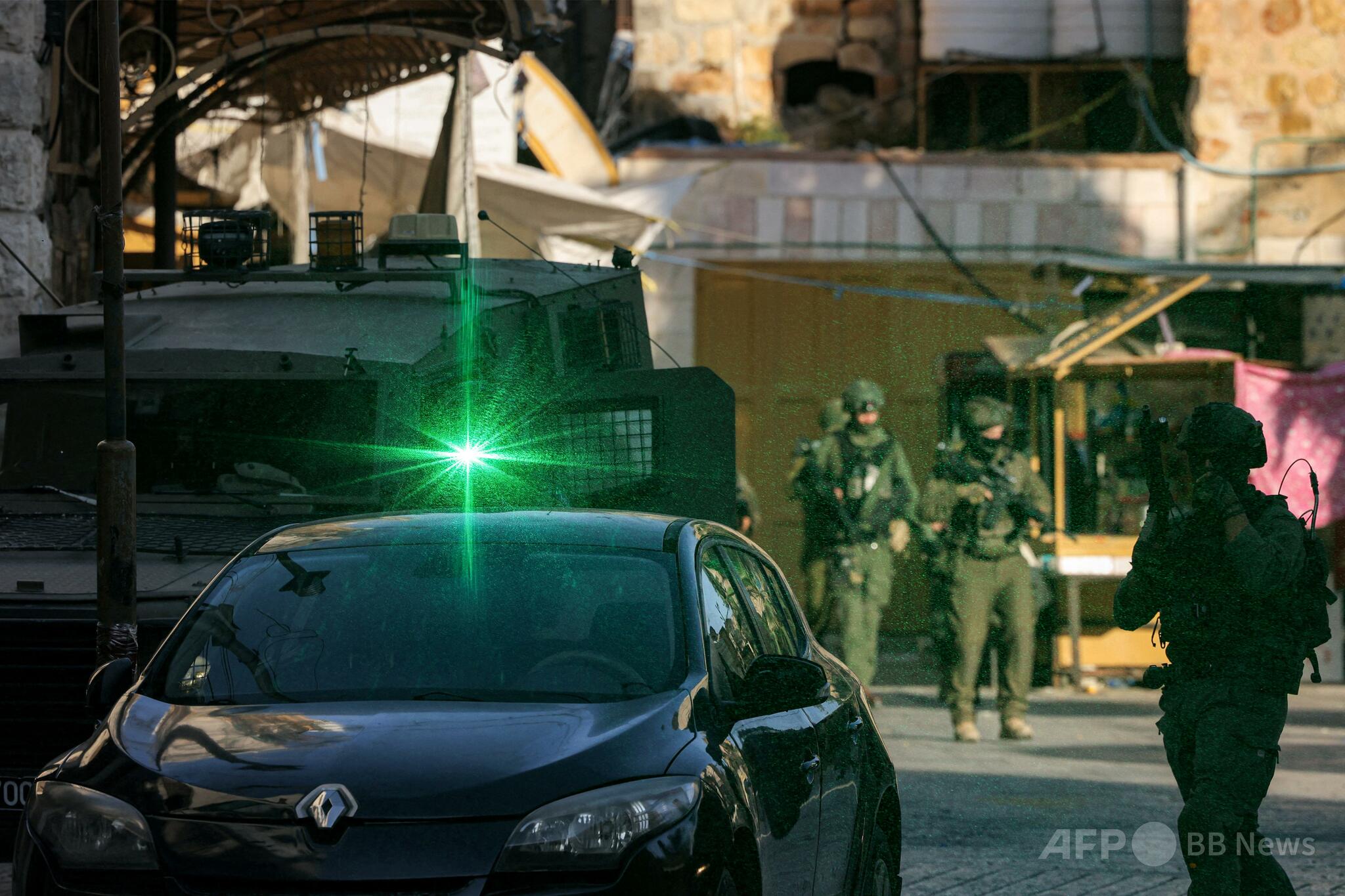 ヨルダン川西岸ヘブロンの旧市街で警戒に当たるイスラエル兵とイスラエル入植者。この地域では入植者とパレスチナ住民、そしてイスラエル軍の間で緊張が続いている。（2025年6月28日撮影）