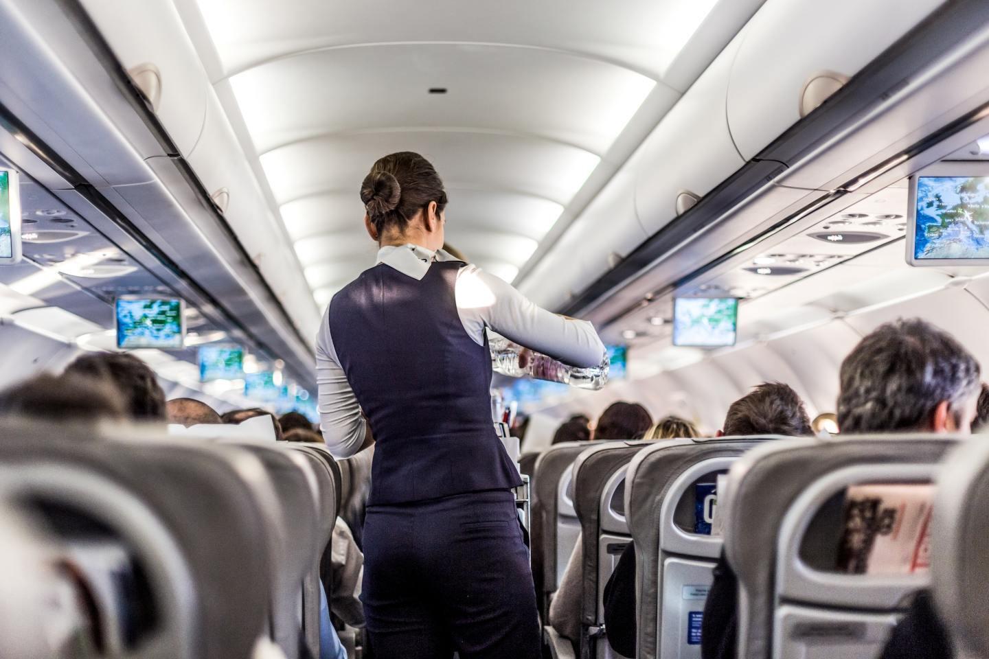 飛行機内で前の座席に足を乗せる乗客のイメージ画像。機内マナーに関する問題提起。