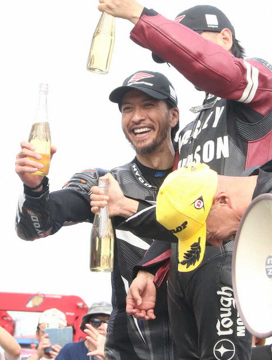 バイクレース後の表彰台で笑顔を見せる長瀬智也