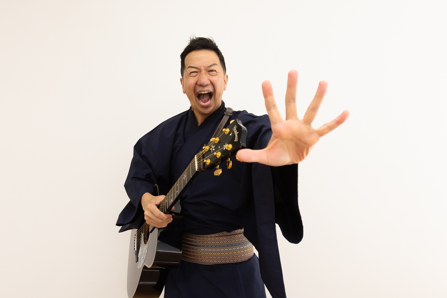 ギターを抱え、「ギター侍」姿でポーズをとる波田陽区氏