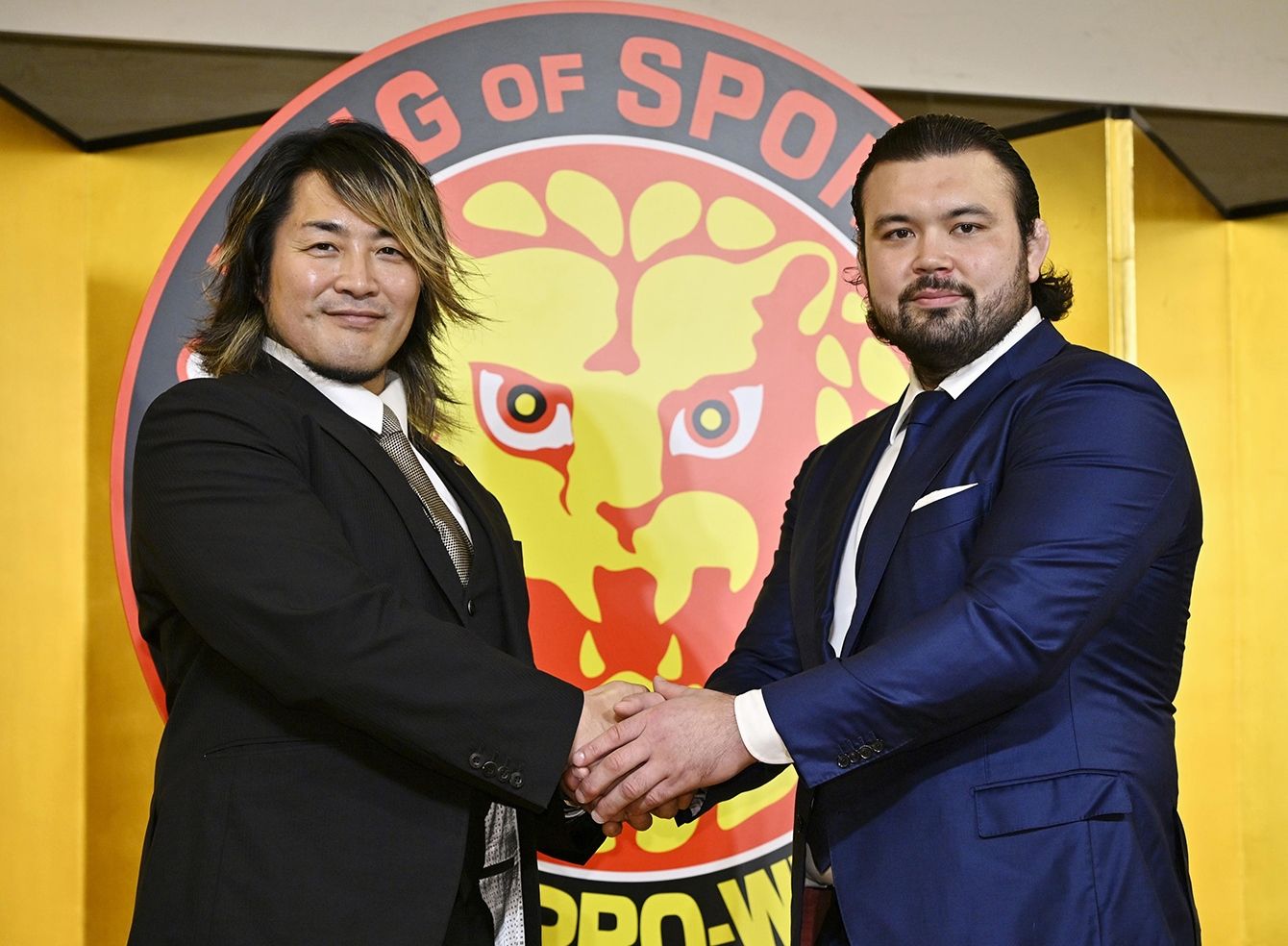 新日本プロレス社長就任後の棚橋弘至が、新戦力のウルフ・アロンと握手する様子