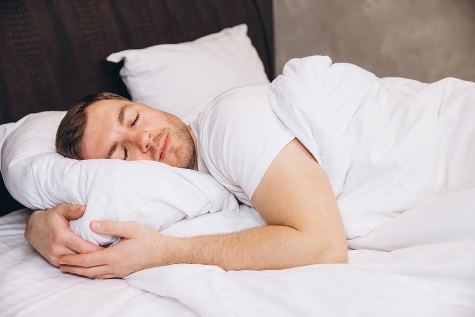 夏の暑さの中、エアコンの効いた寝室で眠る人のイメージ。快眠のためのエアコン冷え対策の重要性を示す画像
