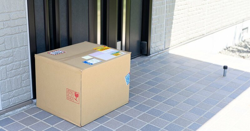 宅配便の荷物を玄関先に置く配達員のイメージ。再配達削減につながる「置き配」の普及が期待される。