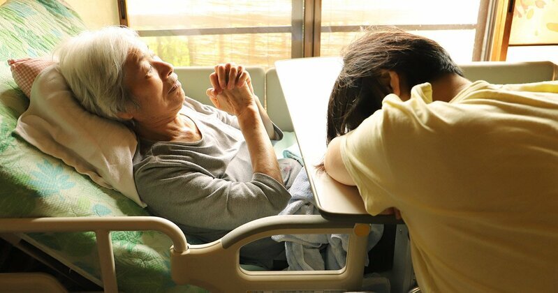 高齢の親の手を握る子の手、介護の様子をイメージ