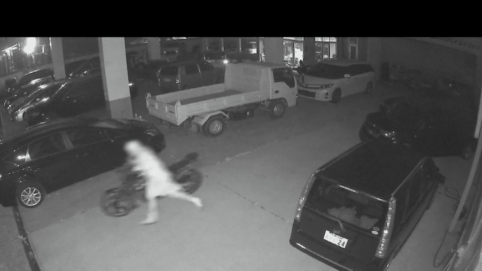 夜間の中古車販売店でライトを照らし、物色する不審な2人組の様子