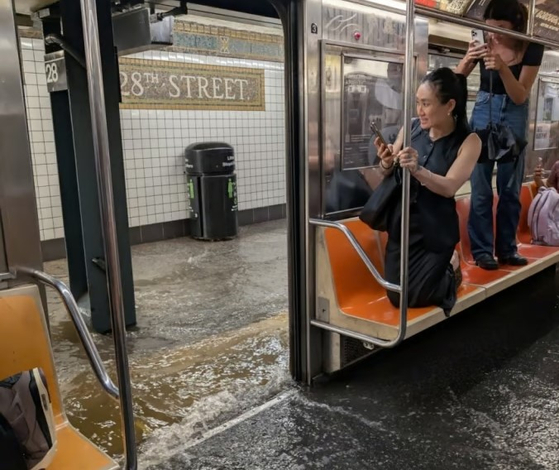 ニューヨークの記録的豪雨で浸水したマンハッタン28丁目地下鉄駅構内、雨水を避ける乗客たち
