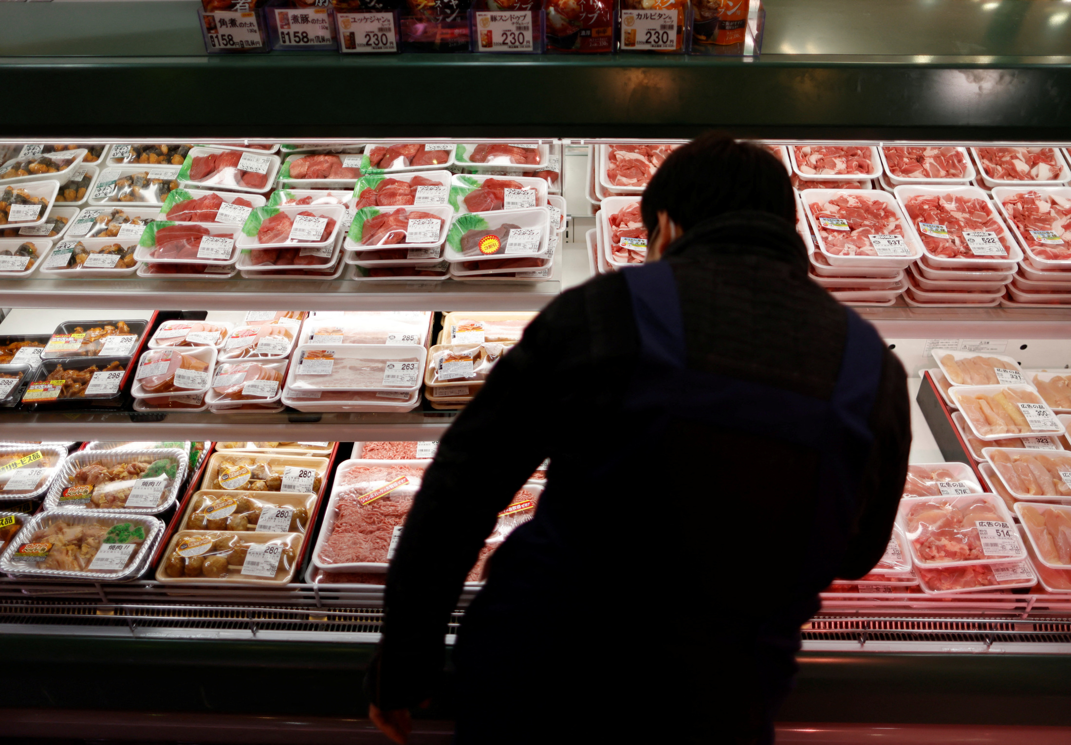 物価高騰が続く中、スーパーマーケットの精肉コーナーで食料品を選ぶ人々。日本のエンゲル係数上昇の背景にある家計の負担増と消費行動の変化を象徴する一枚。食費と消費支出の関連性を示す。