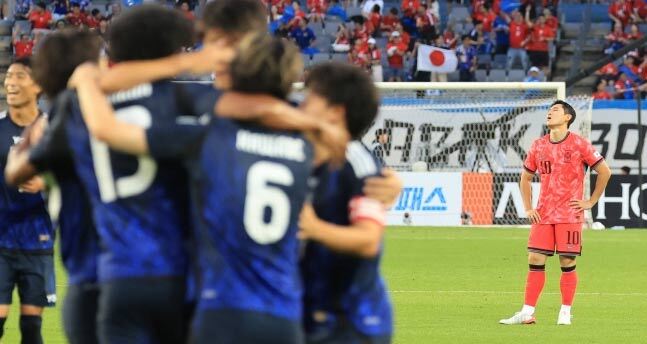 E-1選手権日韓戦で先制ゴールを決め、抱き合って喜ぶ日本代表のジャーメイン良選手たちと落胆する韓国代表選手李東炅選手