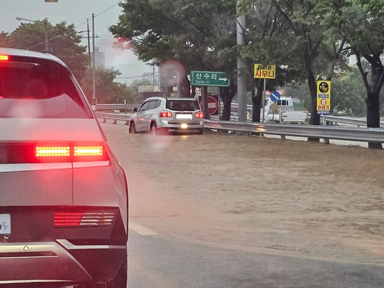 忠清南道瑞山市海美面、大雨で冠水した道路を徐行する車両