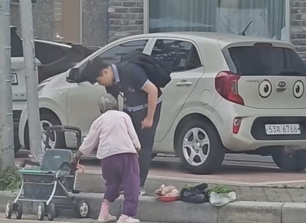 炎天下の路上で、高齢の女性の露店で農作物を買う中学生のオクさん。親切な行動がSNSで拡散された瞬間の映像キャプチャー。