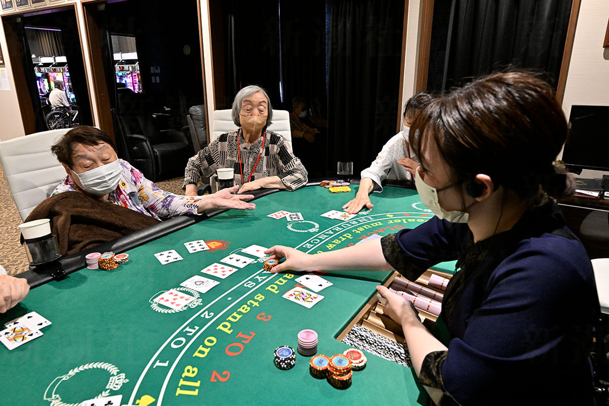 デイサービス「ラスベガス」のポーカーテーブルでゲームに熱中する高齢者女性たち。真剣な表情は、カジノ要素がシニアの活性化と認知機能向上に繋がる可能性を示唆しています。