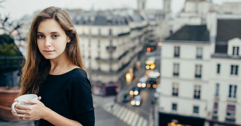 パリのカフェでクロワッサンとコーヒーを楽しむ女性の手元。パリジェンヌの朝食習慣を象徴する光景。