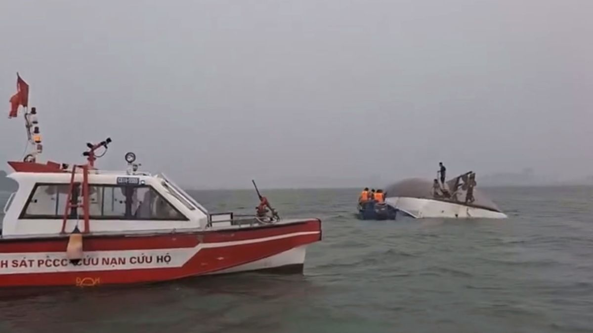 ハロン湾で転覆し、港にえい航される観光船。船体の一部が水面に露出している。