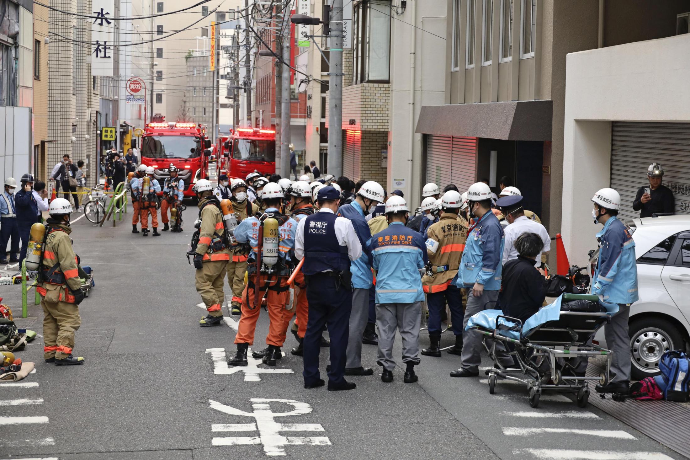 東京都千代田区のビル解体現場で、一酸化炭素中毒事故発生後、集まる消防隊員たち。アスベスト除去作業中の密閉空間における安全対策の重要性を示す事例。