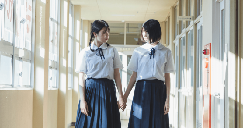 大学の卒業式で空に帽子を投げる学生の姿。学歴と将来のキャリア形成を象徴するイメージ。