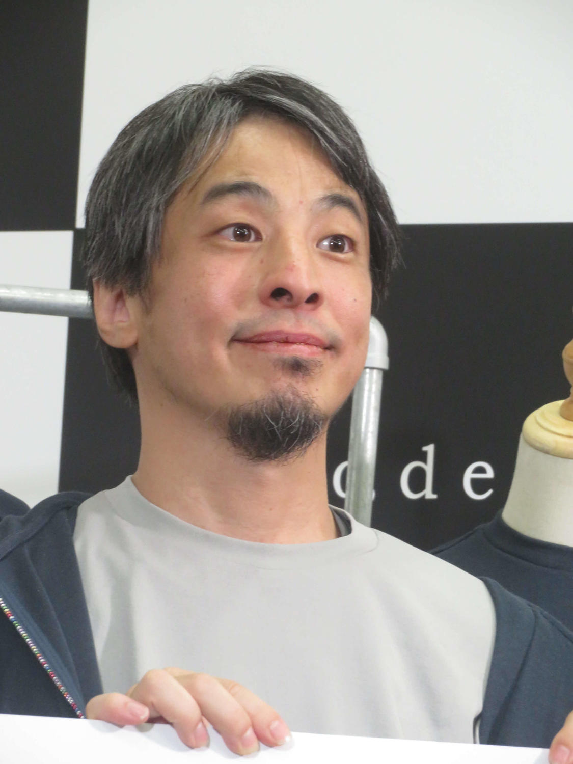 ひろゆき氏（西村博之氏）が真剣な表情でカメラを見つめるポートレート。日本の少子化問題に関する討論に参加した際の姿を想起させる。