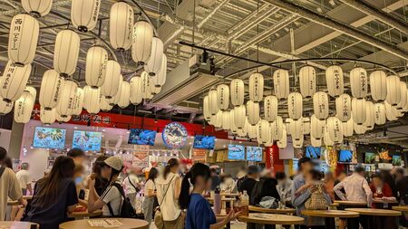 大阪・関西万博「サスティナブルフードコート 大阪のれんめぐり」でハイボールを片手に食事する様子。多くの批判を集めた「立ち食い強制」フードコートの実態を現地で検証する。