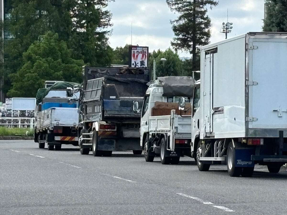 大阪市鶴見区の幹線道路に列をなして路上駐車する大型トラックの様子