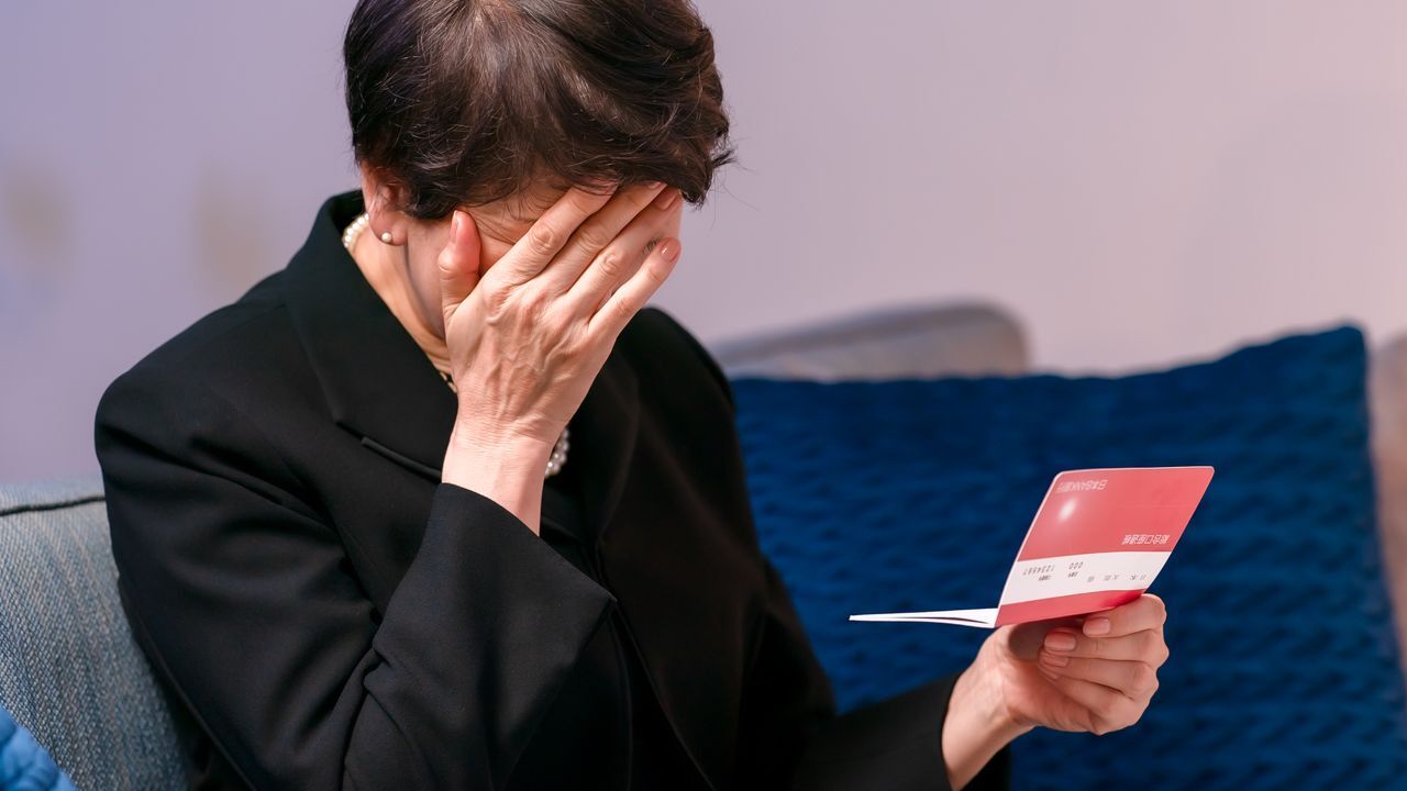 老後の家計に不安を感じ、通帳を確認する女性の姿。夫婦の貯蓄が突然激減する現実と、老後破産の危険性を示唆するイメージ。