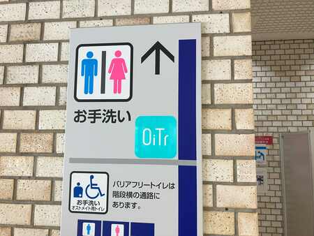 江東区役所のトイレに設置されたOiTr（オイテル）のディスペンサーと、無料生理用品の提供を示すマーク。公共施設での生理用品無償提供の取り組みを示す写真。