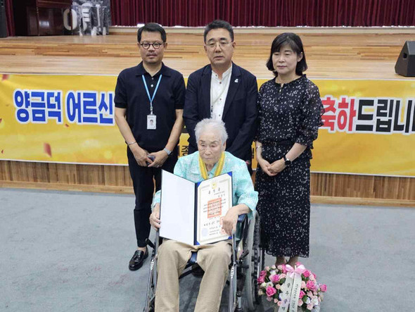 国家人権委員会から大韓民国人権賞を受賞し、笑顔を見せる強制動員被害者のヤン・クムドク氏。中央前で勲章を手にしている。