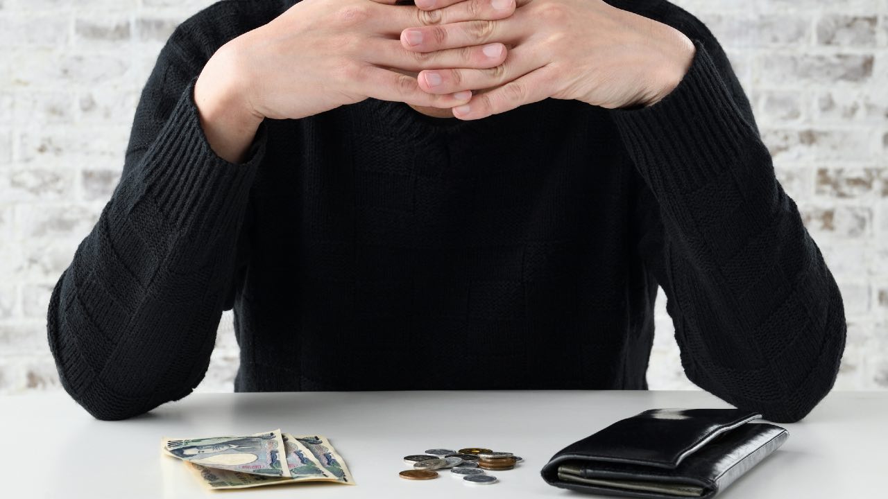 年金手帳と積み重ねられた硬貨のイメージ。就職氷河期世代の年金受給の厳しさを象徴。