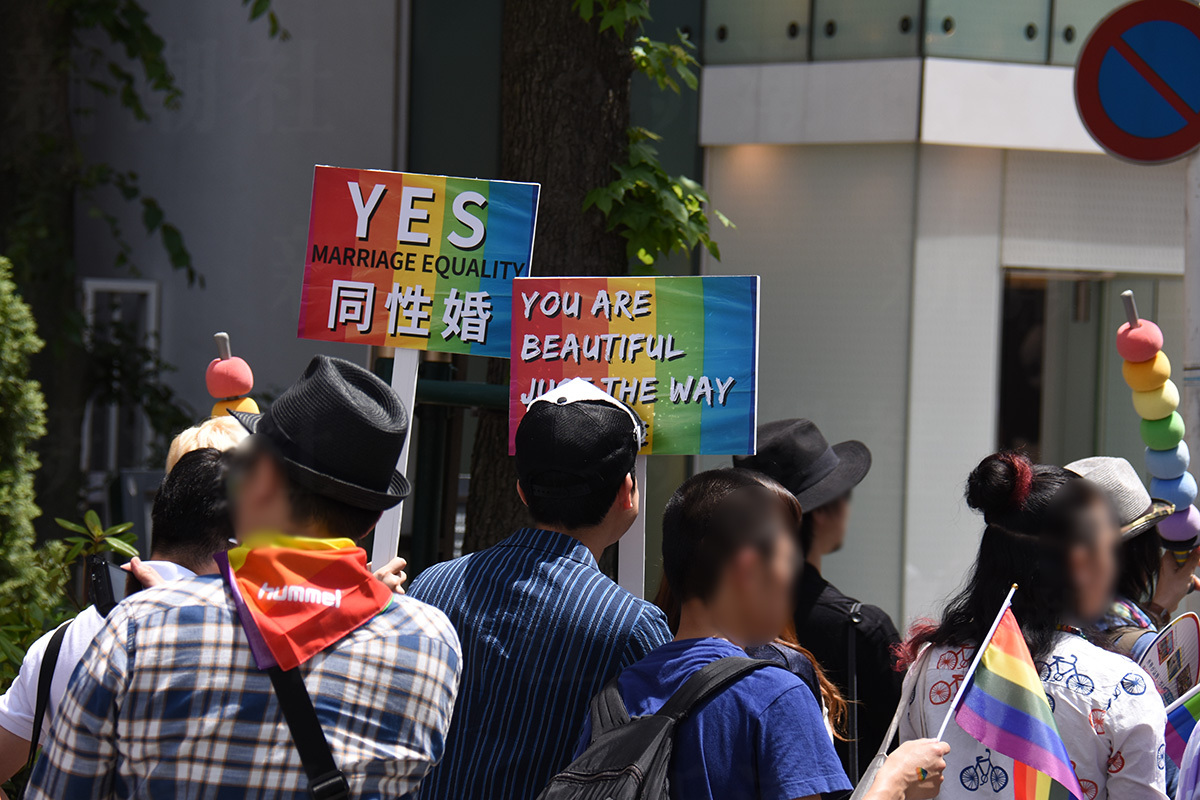 LGBTQの権利を求めるパレード参加者がレインボーフラッグを掲げて行進する様子