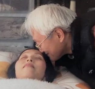 妻の恭子さんに寄り添い、優しく抱きしめる板さん。ALSとの闘いにおける夫婦の絆と愛情を示す瞬間。