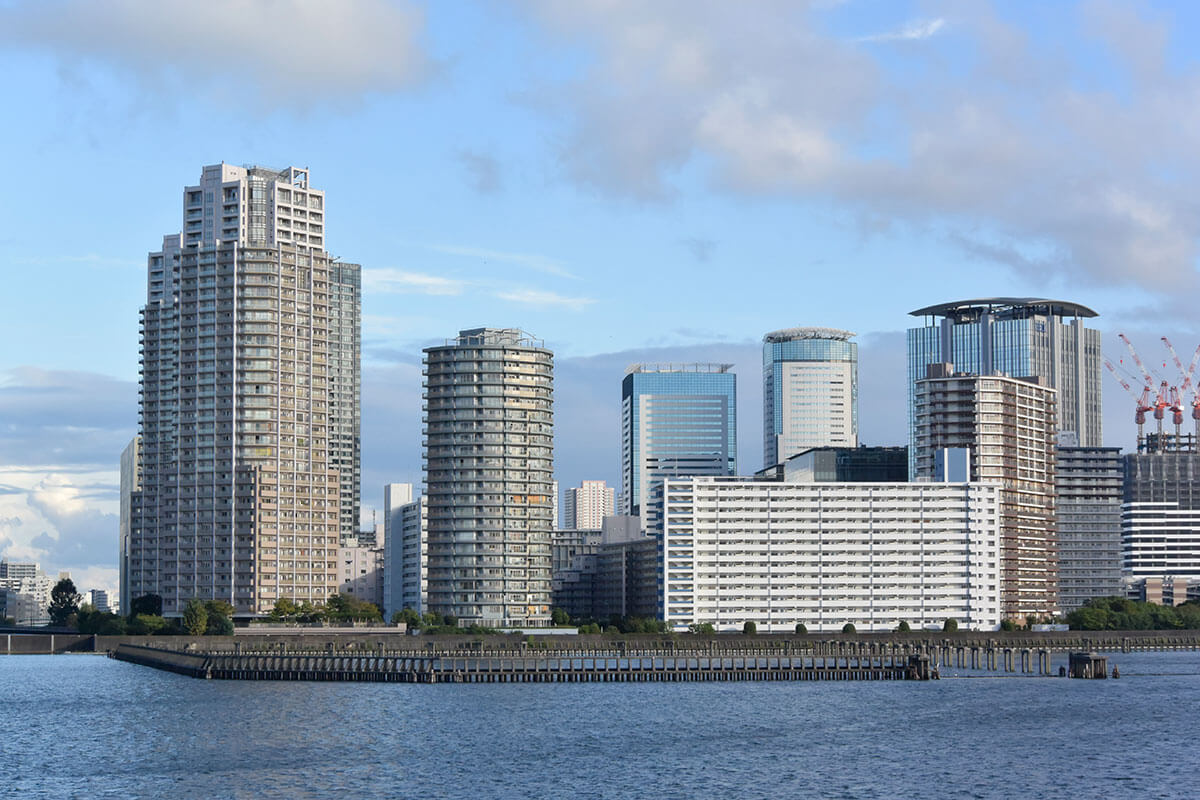 湾岸エリアの高層マンション群と上昇する不動産価格のイメージ