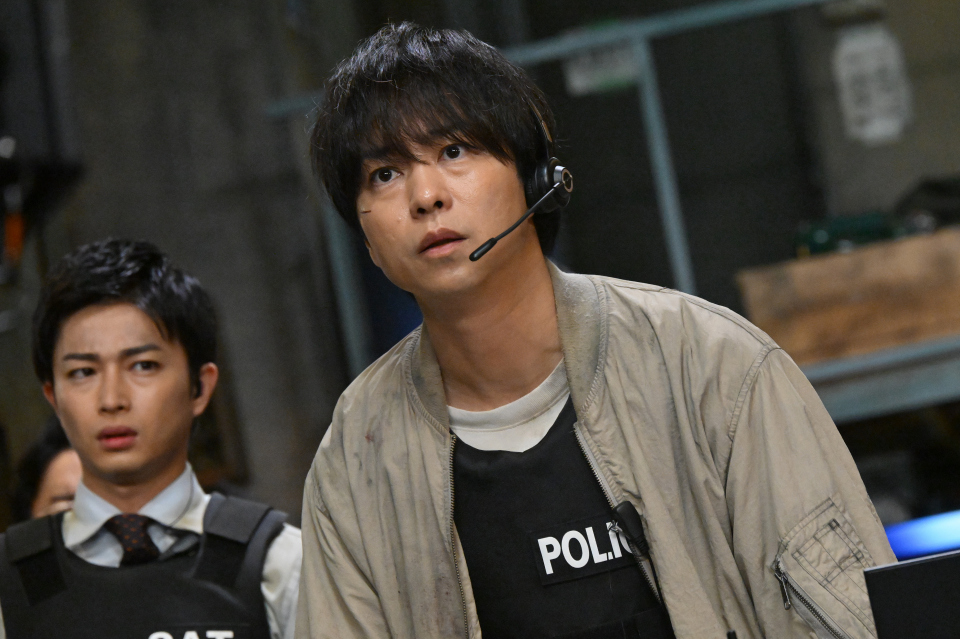 放送局占拠 第6話のワンシーン。緊迫した状況の武蔵三郎（櫻井翔）が描かれており、物語の核心に迫る展開を示唆している。