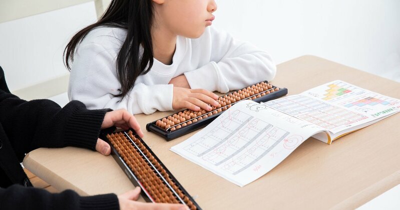 小学生の女の子が自宅の床で本を読んでいる様子。放課後の自由な時間を過ごし、集中して読書に没頭している姿は、子どもに必要な「余白時間」を象徴している。