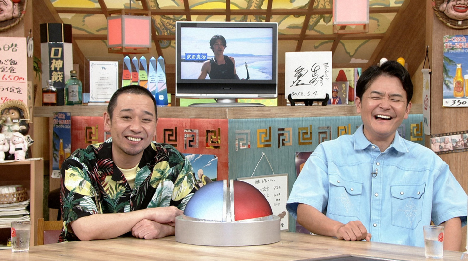 ABCテレビ『相席食堂』に登場するお笑いコンビ・千鳥のノブと大悟。彼らは番組スタジオでVTRを視聴し、ゲストの真島なおみの旅にコメントしている様子。