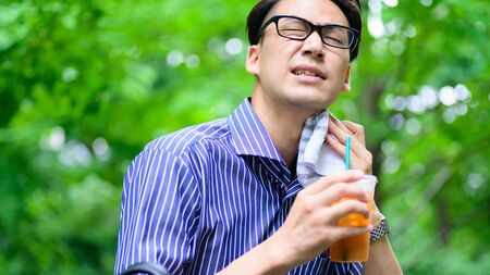 夏バテ対策を考える人物が冷たい飲み物を飲んでいる様子。水分補給の重要性と、冷たいカフェイン飲料が疲労に与える影響を考察する。