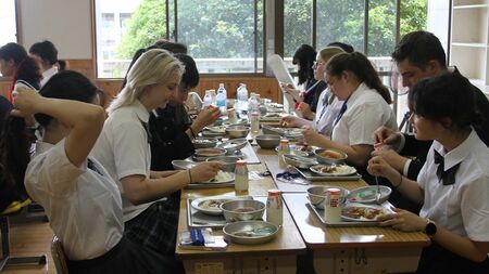 訪日外国人観光客が日本の制服を着用し、学校の廊下で学園生活を疑似体験する様子