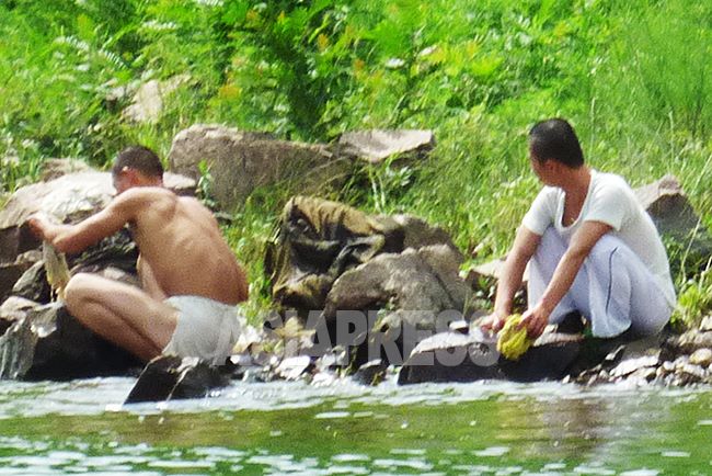 北朝鮮の鴨緑江沿いで水浴びや洗濯をする若い国境警備兵。やせ細った兵士の姿も見える。
