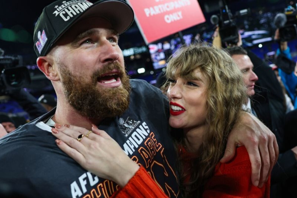 テイラー・スウィフトとトラビス・ケルシーが婚約を発表し、花に囲まれ抱き合う写真。クッションカットのダイヤが輝く指輪も見える。