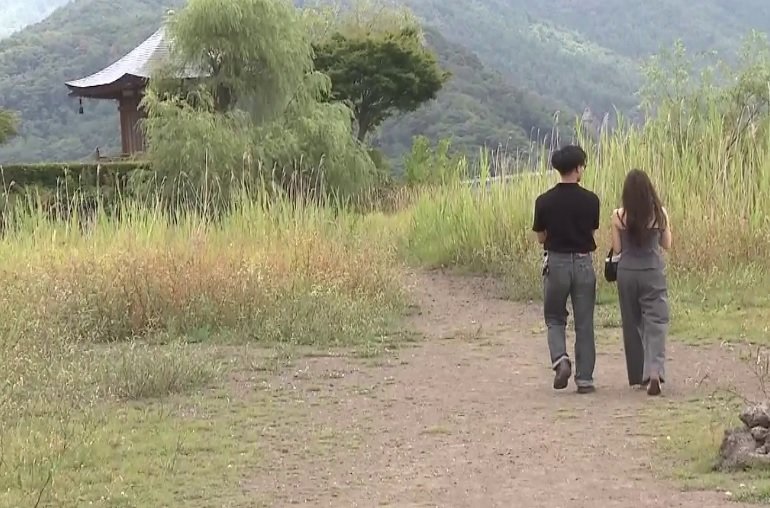 水位が大幅に低下し、六角堂へ続く「幻の道」が出現した河口湖の様子。普段は水没しているはずの道が露わになり、観光客が歩いている。
