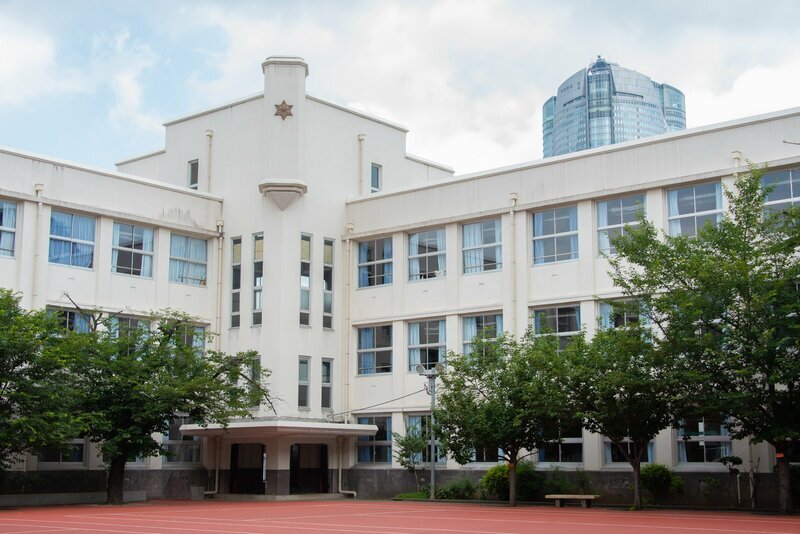 麻布学園の白い校舎と麻の葉文様の校章、背景には六本木ヒルズ