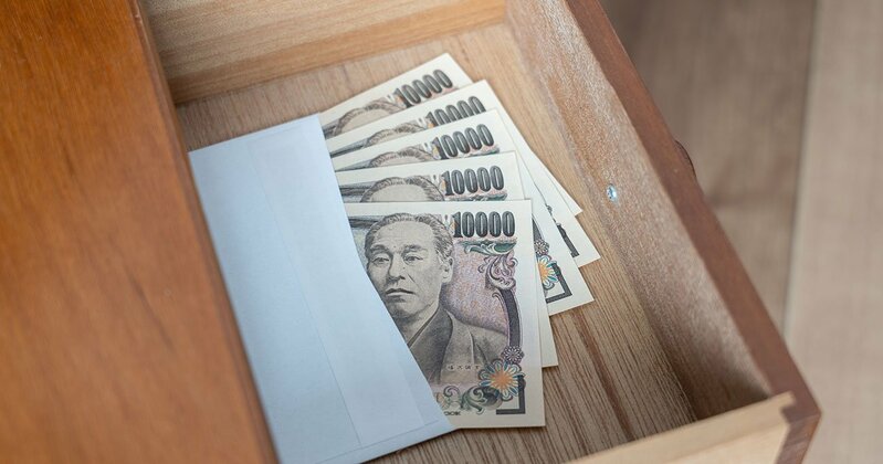 タンス預金と見られる大量の現金が積み上げられている様子。相続税調査で発覚するリスクを示唆。