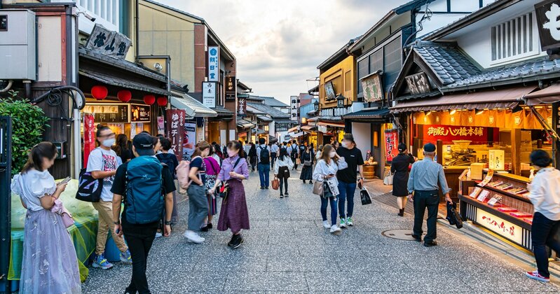 京都市内で外国人観光客と地元住民が行き交う混雑した通り。オーバーツーリズムが市民生活に与える影響を示す風景。
