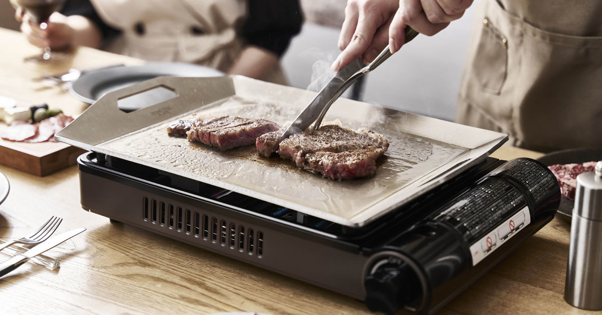 イワタニの新作「ホームシェフプレート」で調理を楽しむ様子。カセットコンロ「焼き上手さん」にセットされ、肉や野菜が均一に焼かれている。