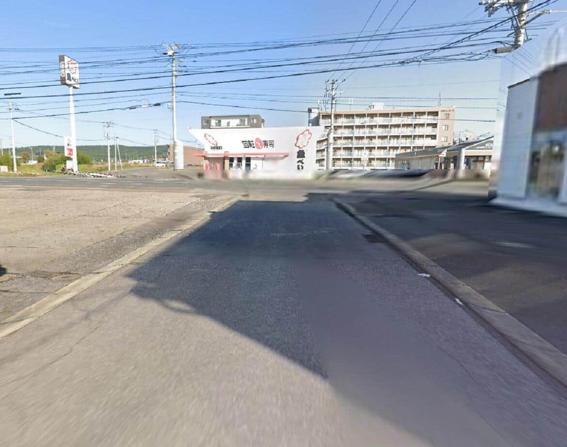 北海道北見市のT字路脇にある回転寿司店「魚べい」に突っ込んだ黒い乗用車。グーグルストリートビューから見た事故現場の様子。
