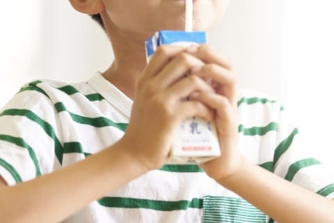 満員電車内でストロー付き紙パック飲料を持つ乗客