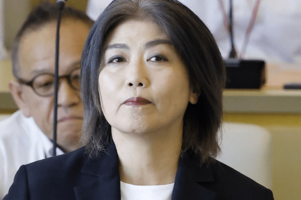 学歴詐称疑惑で不信任決議を可決された静岡県伊東市の田久保眞紀市長が、市議会で真剣な表情を見せる様子。市長の服装と対照的なアニメコラボバッグが注目を集めた。