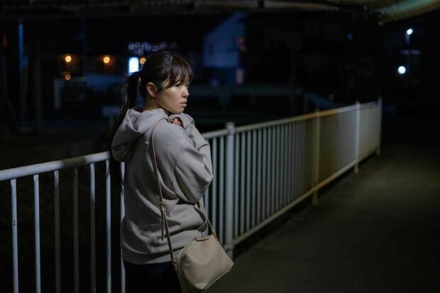夜道を警戒しながら歩く女性のイメージ写真。防犯対策の重要性を示す。